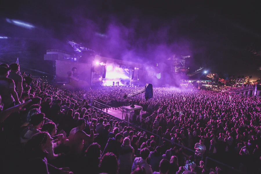 Crowd with hands up in front of a lit concert stage