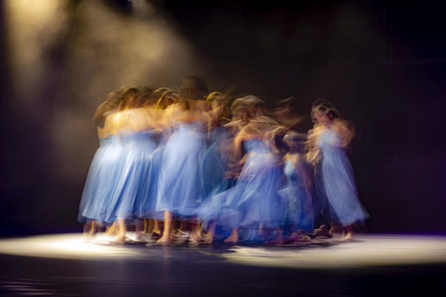 Dancers in blue dresses spinning on stage